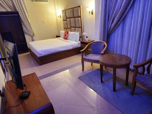 达累斯萨拉姆The Vatican Experience的酒店客房,配有一张床、一张桌子和椅子