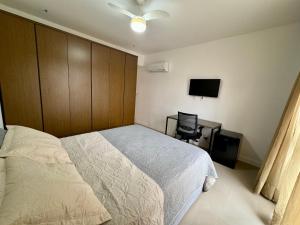 里约热内卢Suite privativa na Barra da Tijuca, RJ - Neolink Stay的一间卧室配有一张床、一张书桌和一台电视