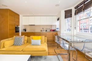 伦敦Lux Duplex near Oxford St的客厅设有黄色沙发和玻璃桌