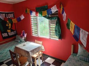 安东尼奥港TOGA GUEST HOUSE的一间设有桌子和配有祈祷旗帜的窗户的客房