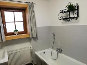 希格斯多夫Ferienwohnung zum Gimpei的带浴缸的浴室和窗户。