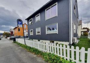 波多Koselig rom med stue i Bodø sentrum的一条街道旁的蓝色房子,有白色的围栏