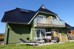 博恩Ferienwohnung de Windroos的绿色的房子设有阳台和桌椅