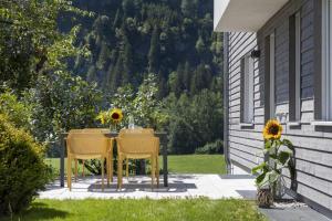 奥巴拉马高Ferienwohnungen Friedenshöhe in Oberammergau的一张桌子,两把椅子,一张桌子,上面有向日葵
