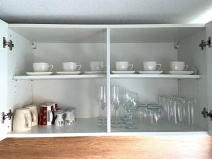 瓦尔斯罗德NEU Ferienwohnung Walsrode的白色的橱柜,上面有盘子和眼镜