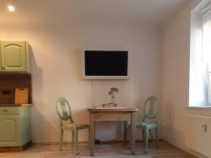 吕本瑙Zur alten Gurkeneinlegerei的一间设有一张桌子和两把椅子的房间,墙上设有一台电视机