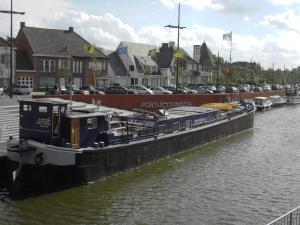 Drie GrachtenCozy Boat in Merkem near Lake的一艘大船停靠在一条有车的河流中