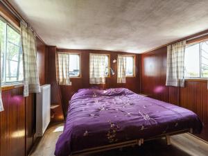 Drie GrachtenCozy Boat in Merkem near Lake的一间设有窗户的客房内的带紫色床的卧室