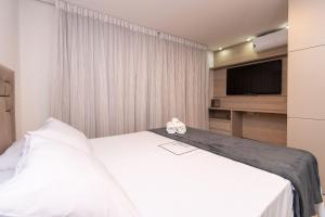 戈亚尼亚Charmosos Flats no Setor Bueno TXP的一间卧室配有两张床和一台平面电视