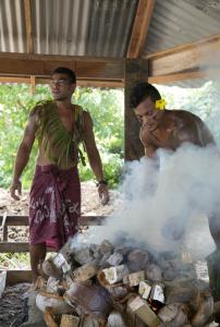 Fausaga椰子海滩俱乐部度假酒店&Spa的两个人在烤架上用烟烤