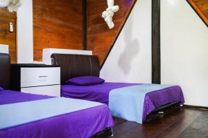 比哈尔Sumatra Surf Resort的配有紫色和白色床单的客房内的两张床