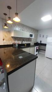阿拉亚尔-杜卡布Casa de Temporada no Paraíso de Arraial do Cabo的厨房配有黑色台面和白色家电