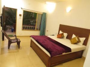 马尔万Blue Sea Beach Resort Malvan的卧室配有床、椅子和窗户。