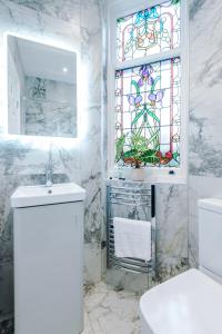 斯托克波特Hilltop Serviced Apartments - Stockport的一间带水槽和彩色玻璃窗的浴室
