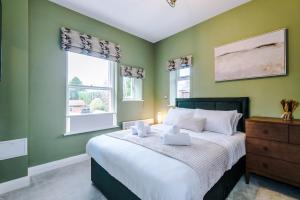斯托克波特Hilltop Serviced Apartments - Stockport的一间卧室设有绿色的墙壁和一张带白色枕头的床。
