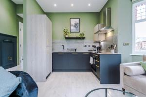斯托克波特Hilltop Serviced Apartments - Stockport的厨房设有蓝色橱柜和绿色的墙壁