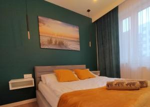 托伦Apartament nr15 z parkingiem podziemnym的一间卧室设有绿色的墙壁和一张带橙色枕头的床