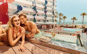 普拉亚登博萨Ushuaia Ibiza Beach Hotel - Adults Only-Entrance to Ushuaia Club included的坐在游泳池旁的男人和女人