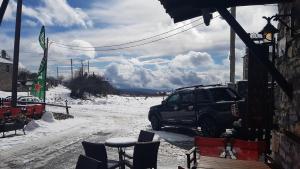 帕雷斯阿吉萨那Patriko Mountain Chalet的停在建筑物外的雪地里的一个汽车