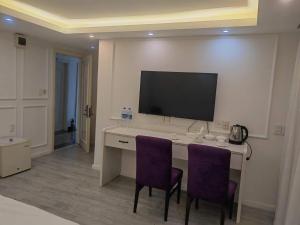 HofoaLATA HOTEL的客房设有一张带两张紫色椅子的桌子和一台电视机