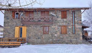 古多里Snowpeak Chalet Gudauri的一座石头建筑,设有黄色的门和阳台