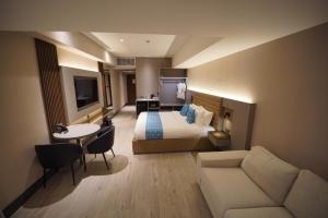 马尼拉Bayprime Hotel的酒店客房配有床、沙发和桌子。