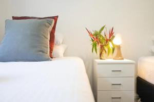 拜伦湾拜伦湖滨假日公寓的配有枕头的床和植物床头柜