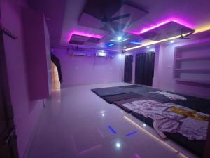 BamrauliDivine INN hotel and guest house的一间紫色灯和一张床铺的房间
