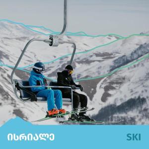 巴库里阿尼Kokhta - Mitarbi Apartment , Bakuriani的两人在雪覆盖的山上乘滑雪缆车