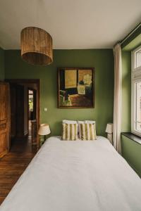 罗什福尔Maison Comtale的绿色卧室配有一张带两个枕头的大床