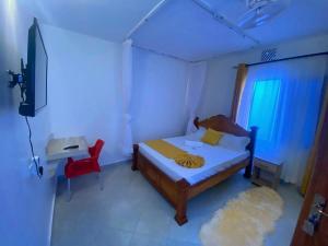 姆特瓦帕Mtwapa Texas Villa Guest House的一间卧室配有一张床、一台电视和一张红色椅子