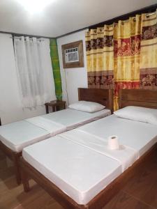 圣维森特Ziah's Guest House的配有窗帘的客房内的两张床