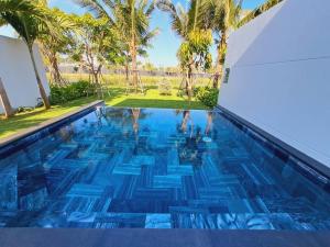 后川Sanctuary Ho Tram Villa的一座拥有蓝色海水和棕榈树的游泳池