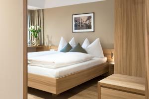 劳特阿赫Hotel Johann Lauterach的一间卧室配有带白色床单和枕头的床。