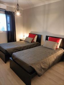 波瓦桑Sons da Ribeira的一间卧室配有两张带红色枕头的床