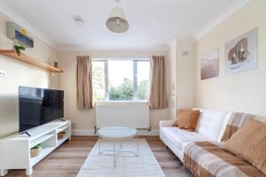 伦敦Lovely Studio Flat in Wimbledon w/ Free Parking的客厅配有白色沙发和电视