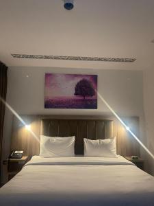 安曼Antalya Hotel Amman的卧室配有白色的床和墙上的绘画作品