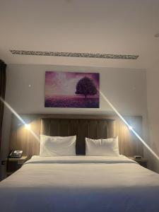 安曼Antalya Hotel Amman的卧室配有一张白色床,墙上挂有绘画作品