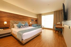 新德里印度必兹诺酒店的酒店客房设有一张大床和一张书桌。