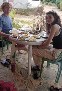 纳拉坦尼亚Vegetable Garden House的坐在餐桌旁吃饭的男人和女人