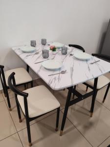 大山脚Cozy 2room 6pax @ Menara Sentral的一张带椅子和盘子的白色桌子