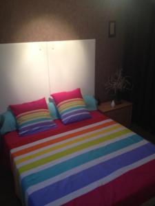 奥弗涅库尔农喇叭花住宿加早餐旅馆的床上配有色彩缤纷的毯子和枕头