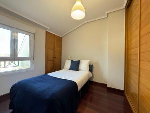 埃拉斯蒂列罗Fantástico Dúplex Vista Bahia的一间卧室配有一张带蓝色毯子的床和窗户。