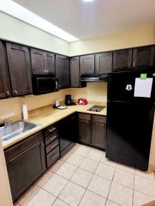 奥兰多lovely entire Suite with kitchen 5 Min to Disney的厨房配有木制橱柜和黑色冰箱。