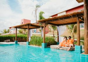 卡皮托利乌Hotel Chalé Capitólio的坐在度假村游泳池边的夫妇