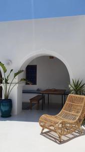 Maison d’hôte, Djerba的一张柳条椅,坐在带桌子的房间
