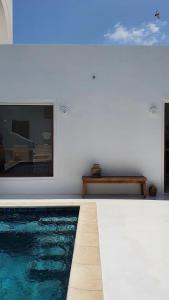 Maison d’hôte, Djerba的一座游泳池,旁边是白色的墙壁,画着绘画