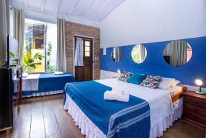 伊利亚贝拉Pousada Recanto da Villa的蓝色和白色的卧室设有1张床和1台电视