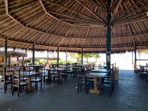 新维索萨Pousada Cheiro de Mar的一间带桌椅和稻草屋顶的餐厅