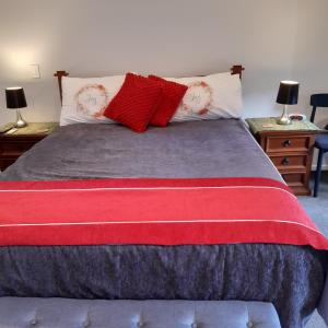 帕帕莫阿Papamoa Beach Hugoway, Pohutukawa Studio Deluxe, Close beach, free parking的一张带红色和白色枕头的床